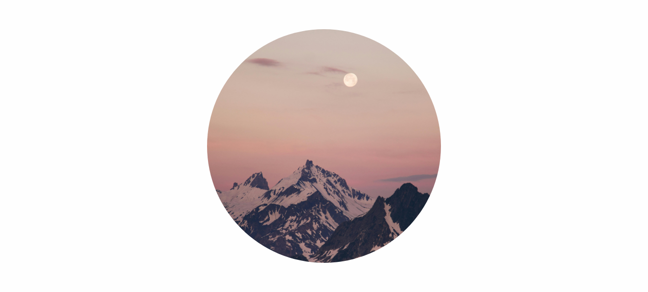 Snow Moon in a pastel sky above mountain peaks, representing February’s full moon themes of clarity, patience, and renewal.