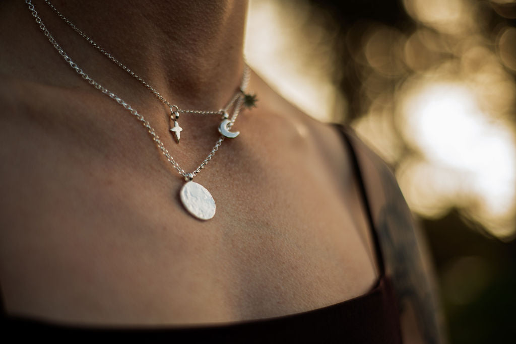 Close-up of layered necklaces including Full Moon pendant with Sun, Moon and Star necklace, showing how jewellery layers on the neckline.
