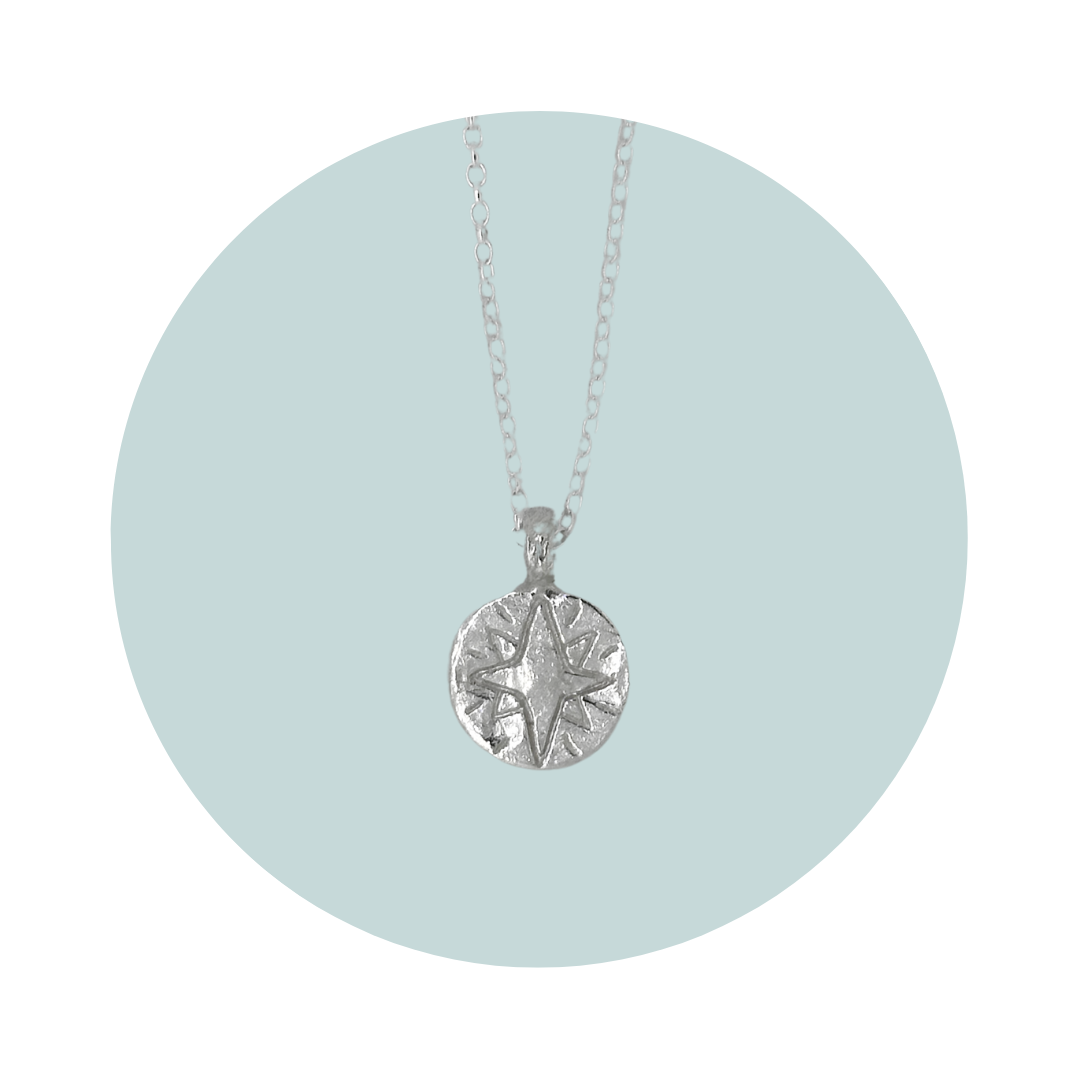 Recycled sterling silver North Star necklace with a hand engraved star symbol, featuring a disc shaped pendant.