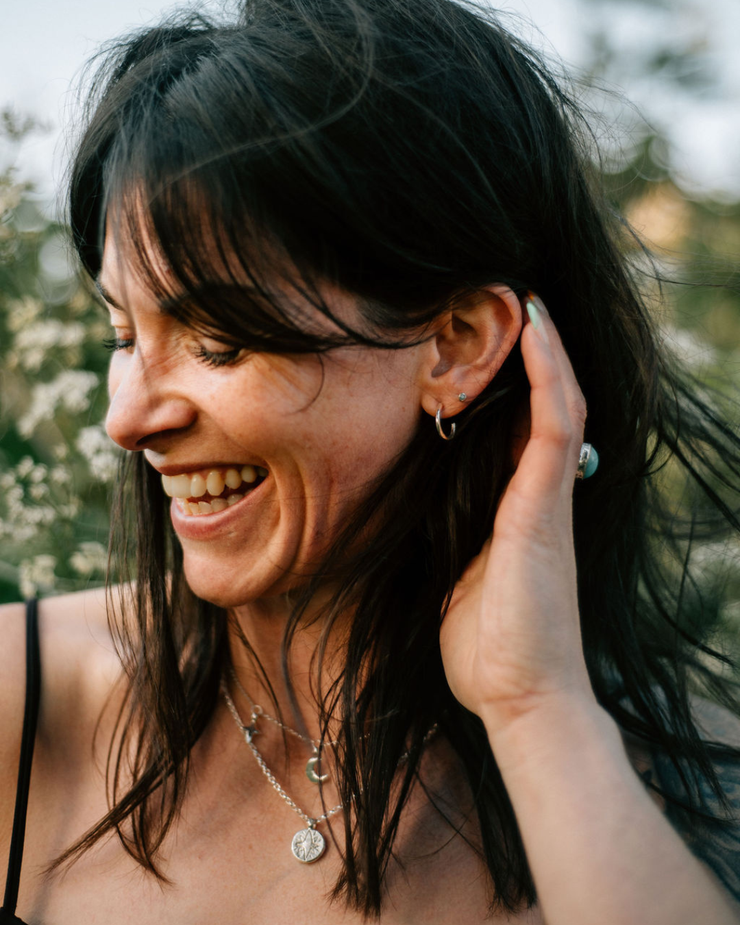 Woman smiling while wearing stud earrings, styled with side part hair, stud earring size guide example.
