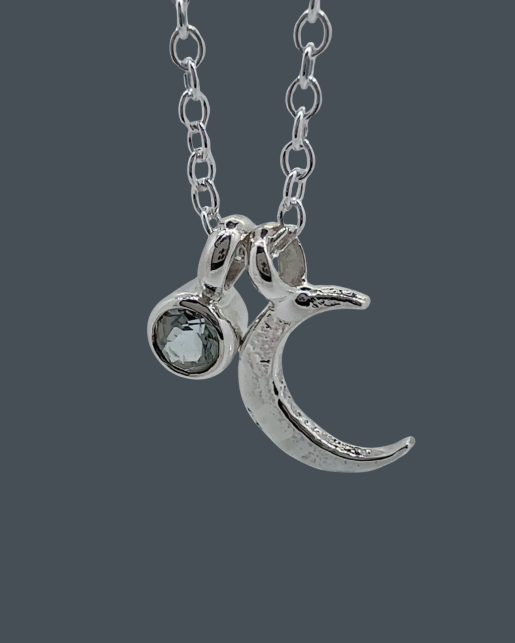 Detailed close-up showing the texture of the sterling silver crescent moon necklace and its 5mm aquamarine charm.