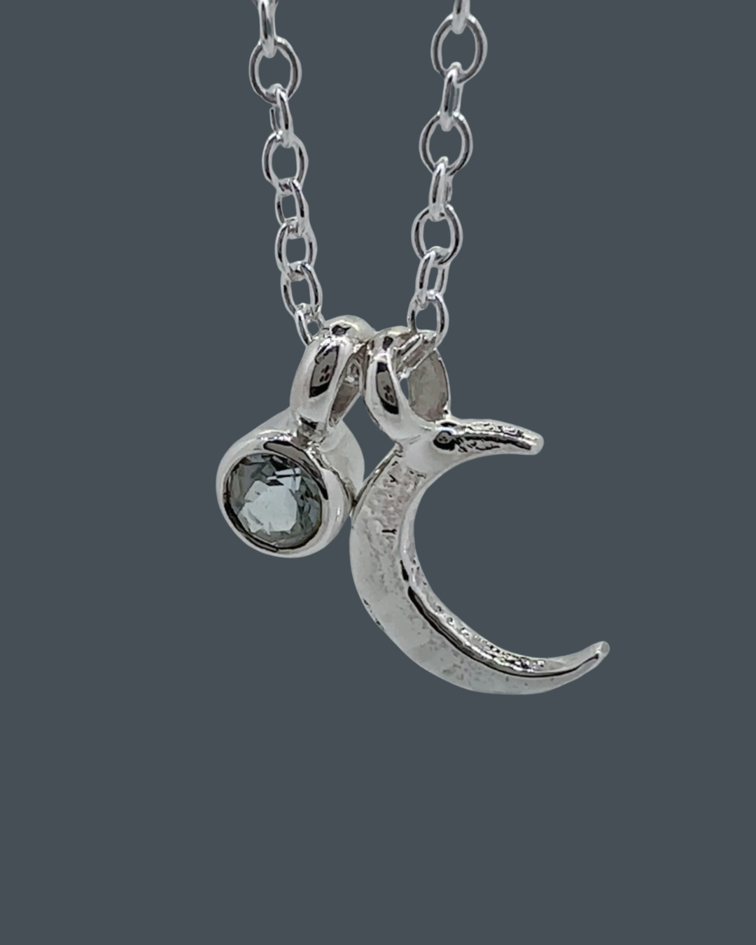 Detailed close-up showing the texture of the sterling silver crescent moon necklace and its 5mm aquamarine charm.