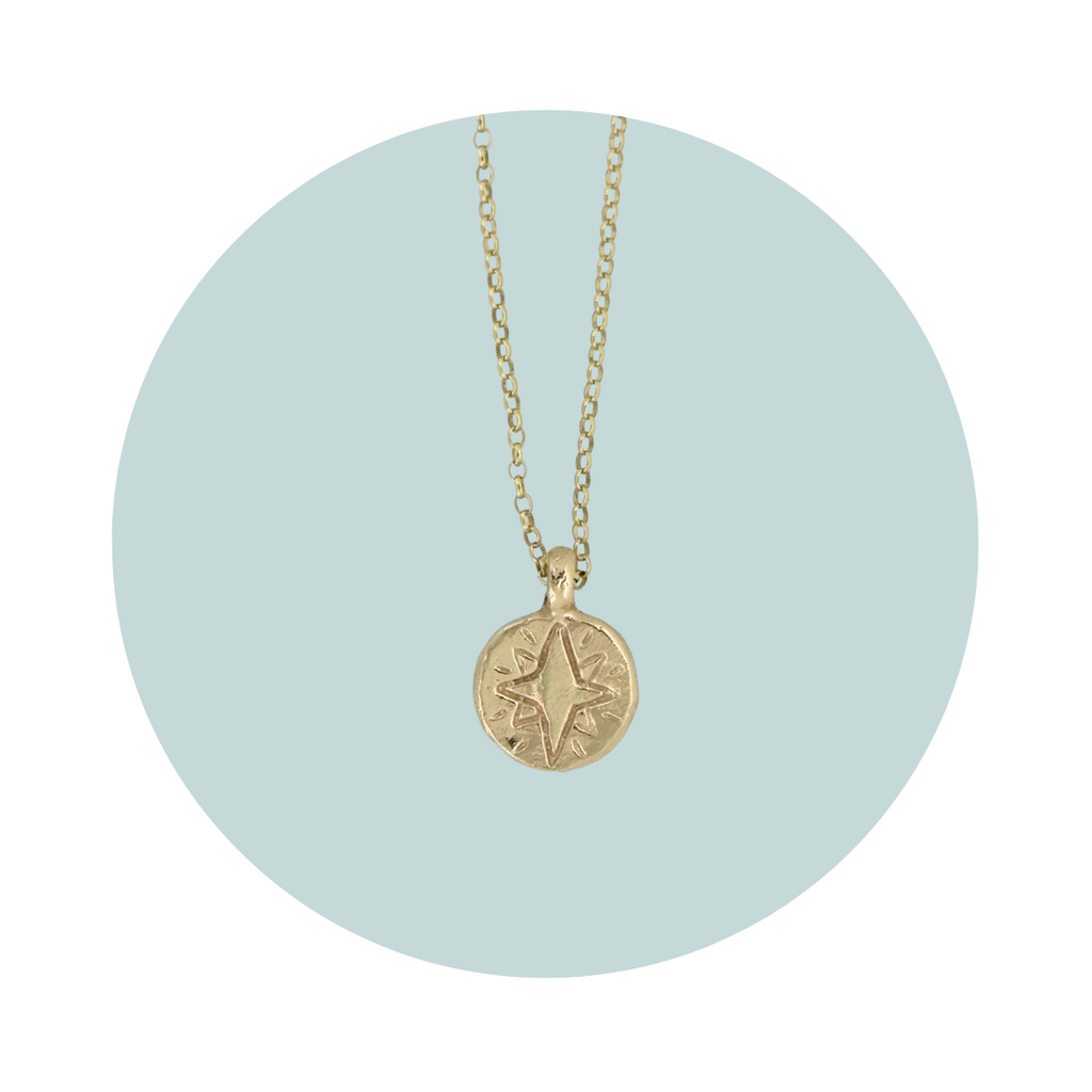 Front view of a gold North Star pendant showing the carved star design.