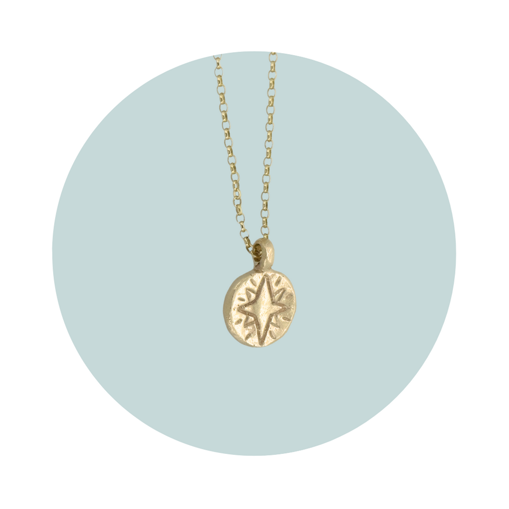 Side view of a gold North Star pendant showing the textured edges.