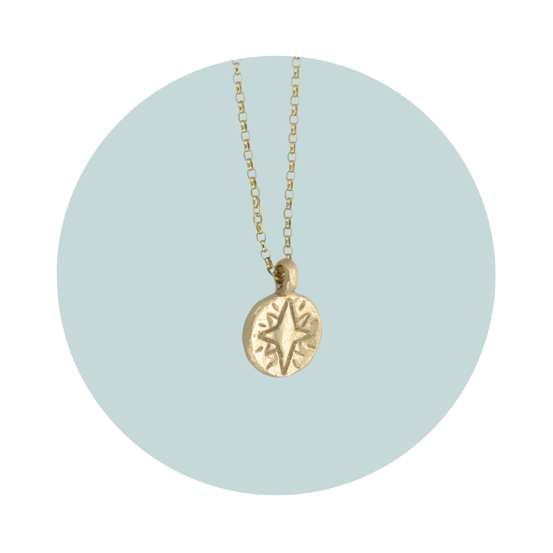 Side view of a gold North Star pendant showing the textured edges.