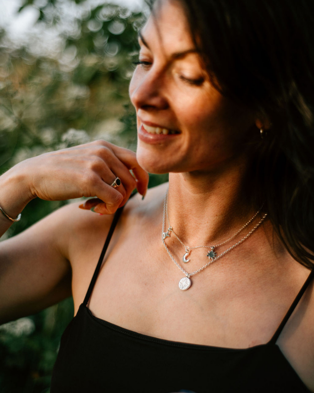 Handmade recycled sterling silver jewellery styled outdoors: North Star disc pendant on 18-inch chain layered with Sun, Moon and All My Stars necklace on 16-inch chain.
