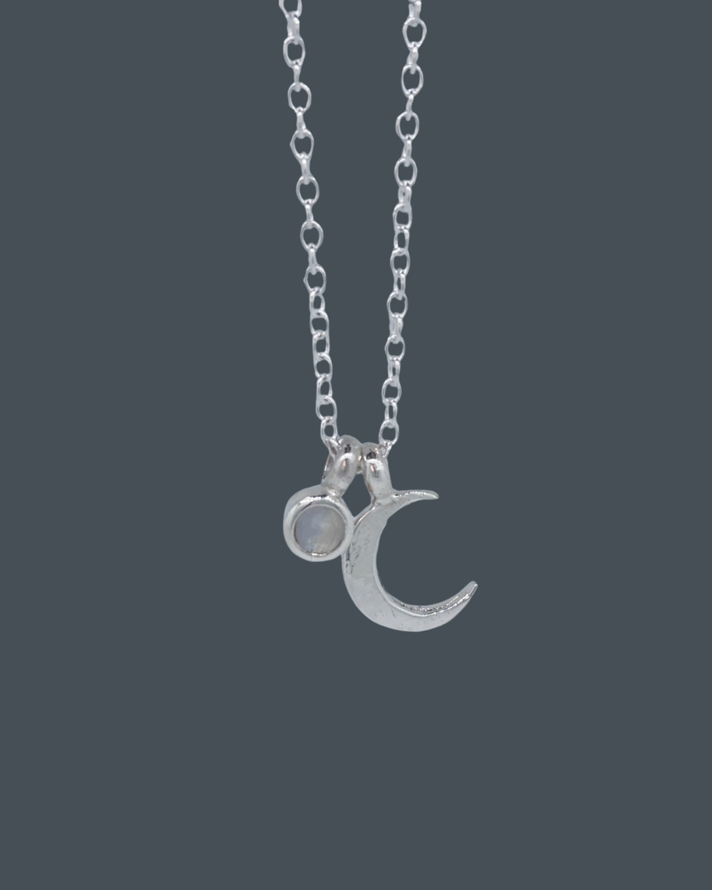 Front-view of a recycled sterling silver crescent moon necklace with a 5mm moonstone charm.