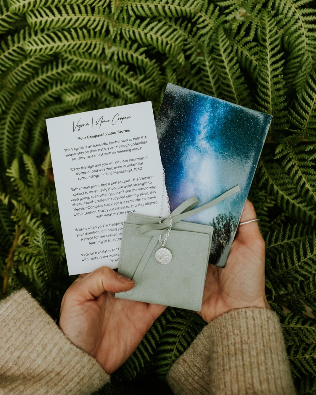 Flat lay of the sterling silver Vegvisir necklace with its story card and jewellery pouch.